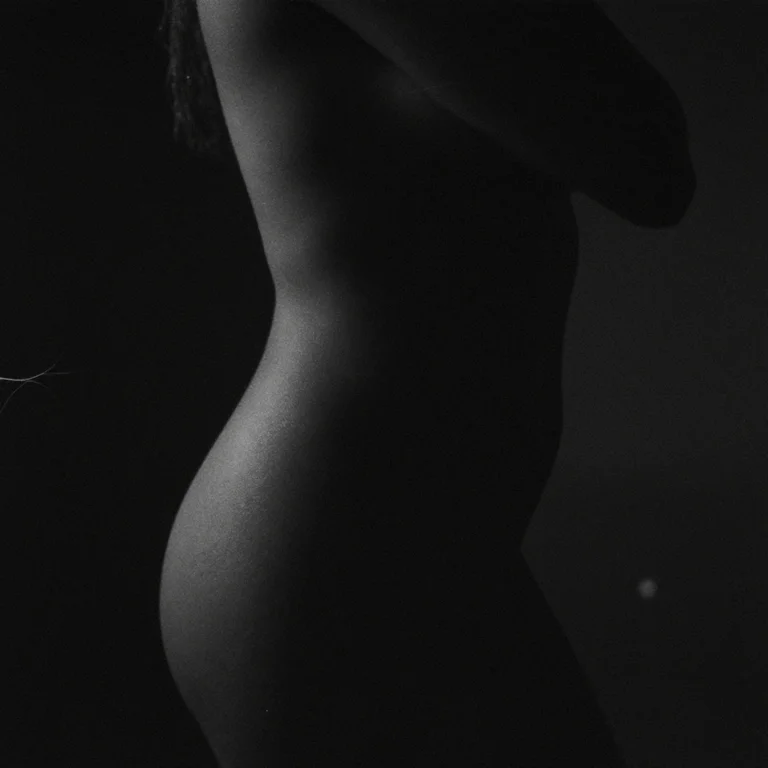 A grainy black-and-white AI silhouette of an adult back and hip in deep shadow