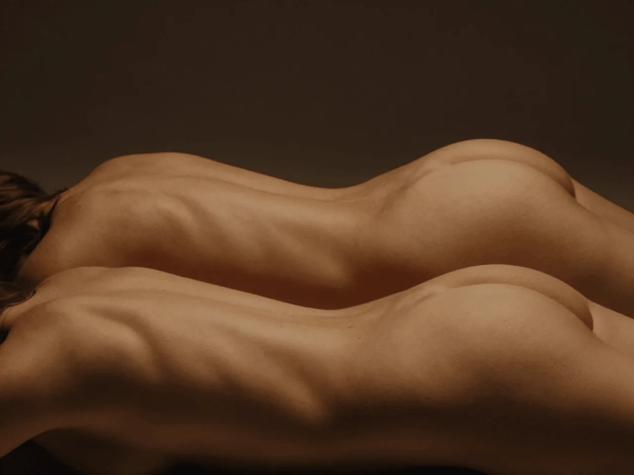 An abstract study of reclining human forms in warm light and soft shadow